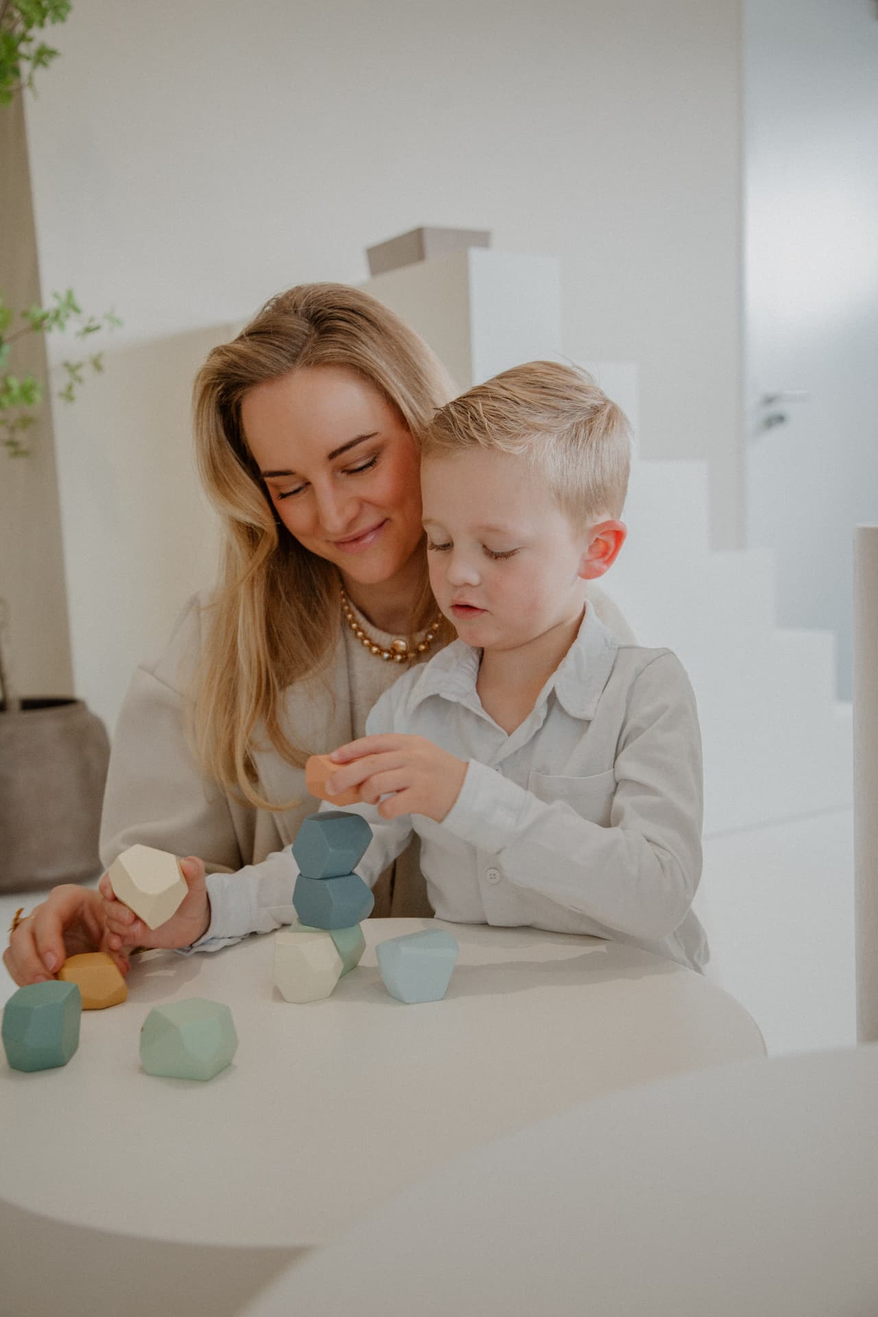 Jade speelt samen met een kind met gekleurde houten blokken